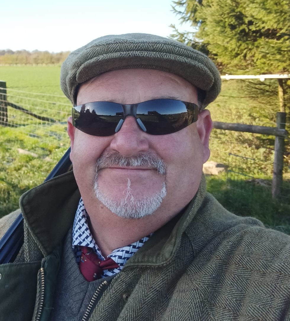man with sunglasses and hat in field