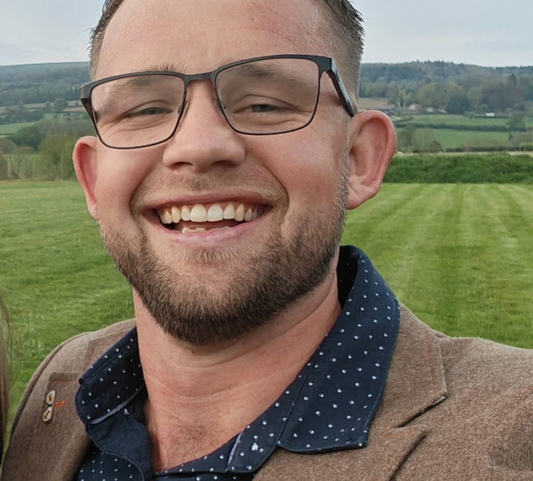 man with glasses and beard in field